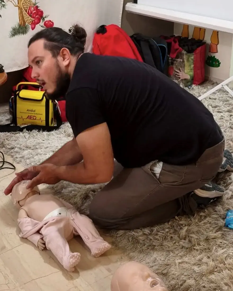 Ο Σίλβιο Κουλλόλλι διδάσκει πρώτες βοήθειες με κούκλα εκπαίδευσης βρέφους, δίπλα σε απινιδωτή